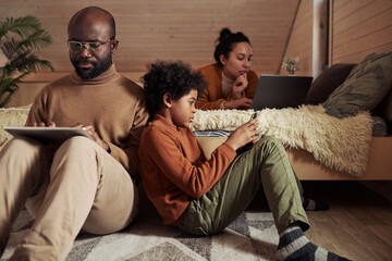 Poster - Cute boy with smartphone sitting on the floor next to his father using tablet while networking or scrolling through online information