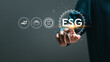 © Pakin - Sustainable development and green business concept. Man touching virtual screen of ESG icons to analyze ESG for ESG environment social governance investment business,  business investment strategy.