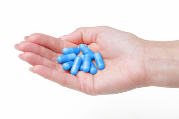 Female hand holding pills. Woman open hand with medicine. Drugs isolated on white background. Blue vitamin capsules on girl hand. Cutout hand holding diet supplement.