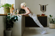 © pressmaster - Side view of aged retired woman in activewear doing press ups against kitchen counter during morning workout after sleep