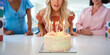 © Monkey Business - Mature Woman At Home Celebrating Birthday With Friends And Blowing Out Candles On Cake