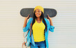© rohappy - Portrait of happy smiling young african woman model posing with skateboard in the city