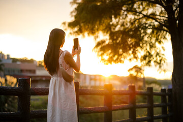 Canvas Print - Woman use of mobile phone to take photo under sunset