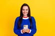 © deagreez - Portrait of young cheerful brunette woman wear blue knitted pullover browsing social media in iphone isolated on yellow color background