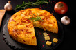 Spanish omelette with potatoes and onion, typical Spanish cuisine on a black concrete background. Tortilla espanola
