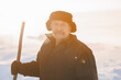 © Parilov - Elderly man cleaning snow with shovel in village after snowstorm. Old pensioner works as janitor, sunlight.