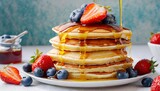 close up delicious pancakes with fresh blueberries strawberries and maple syrup on a light background with copy space sweet maple syrup flows from a stack of pancake