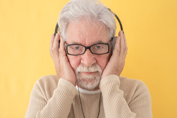 Wall Mural - Closeup portrait of concentrated senior bearded man holding headphones on head listening music