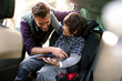 © Davor - Father helping son with tablet in car seat