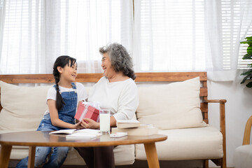 Asian girl surprise and giving her grandmother a present box. Granddaughter visit senior woman on holidays weekend. Family meeting, bonding relationship. Healthy living insurance after retired