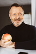 © contrastwerkstatt - Confident Bestager Man Holding an Apple, Making Healthy Nutrition Choices