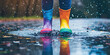 © dinastya - Closeup of pair of brightly colored kids rain boots splashing water through puddles. Water-resistant children's shoes for autumn fall walks in puddles.