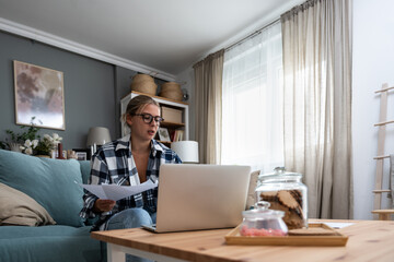 Young freelance business woman working at home on laptop as product strategy expert. Female expatriate remote work on internet on computer online for foreign company as web developer