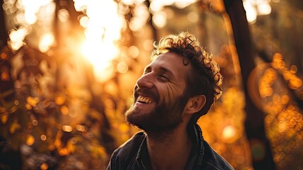 Wall Mural -  a man smiles as the sun shines through the trees in the background of a forest filled with yellow leaves.