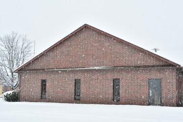 Poster - Snow Falling by a Brick Building