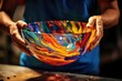 Artisan holds a vividly colored glass bowl with swirling patterns.