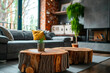 Close-up of two tree stump accent coffee tables near a grey sofa against a window and fireplace, showcasing the minimalist loft home interior design of a modern living room.