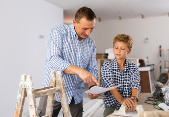 Wall Mural - Young boy having conversation with his father about home improvement works in new apartment. Father and son looking at document.