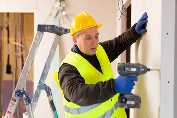 Wall Mural - Caucasian repair man standing in apartment and using drill.