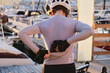 © KatyaPulka - A woman cyclist is putting her cycling vest into the back pocket of her cycling jersey during her bike training. Cycling adventure. Athlete is wearing cycling kit.