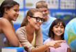 © Mapodile M./peopleimages.com - Happy teacher, students and geography with planet or globe of earth in class for education or learning at school. Woman, mentor or educator smile with kids or children with world map in classroom