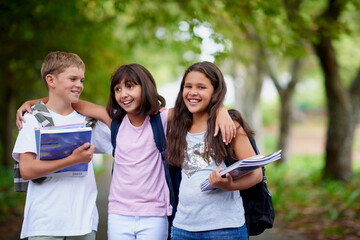 Happy kids, friends and hug with backpack in park for unity, teamwork or walking to school together. Group of young people smile in nature with bag or books for learning, education or outdoor forest