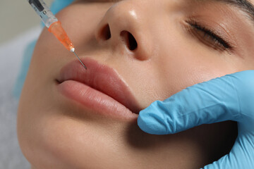 Canvas Print - Doctor giving lips injection to young woman in clinic, closeup. Cosmetic surgery