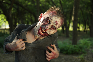 Wall Mural - Scary zombie with bloody face outdoors. Halloween monster