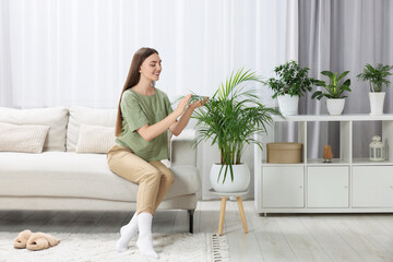 Canvas Print - Beautiful young woman in room with green houseplants