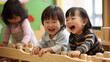 日本の幼稚園児3人が私服で木のおもちゃを使って,笑顔で遊んでいる写真、背景保育ルーム、木育/幼児教育