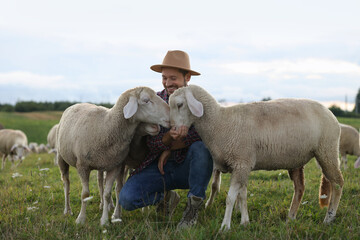 Poster - Smiling man feeding sheep on pasture at farm