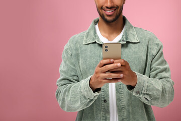 Poster - Man sending message via smartphone on pink background, closeup. Space for text