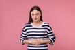 Young woman suffering from stomach pain on pink background