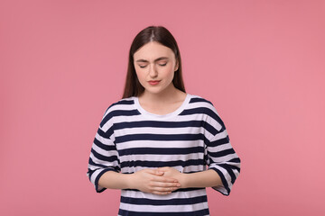 Wall Mural - Young woman suffering from stomach pain on pink background