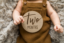 Baby Boy In Overalls Holding A Two Month Old Milestone Sign In His Hands