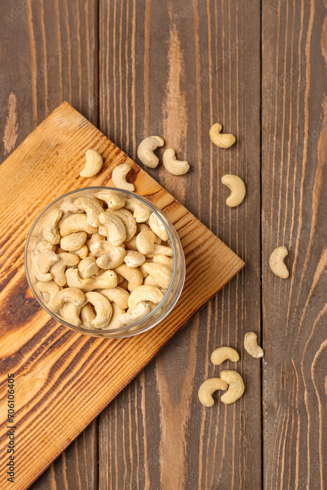 Jar with tasty cashew nuts on wooden background
