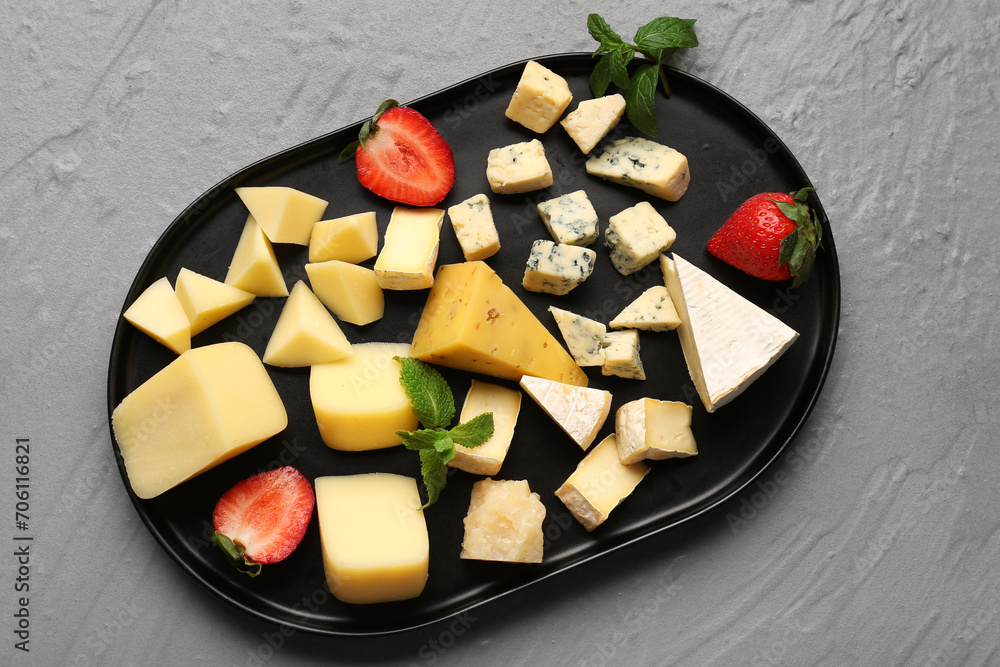Tray with pieces of tasty cheese on grey background