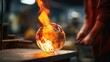 Closeup of a glass blowers flame heating a ball of molten glass, ready to be transformed into a delicate vase.