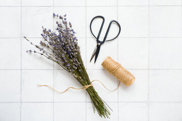 Poster - Scissors with thread and dried lavender on white tile background