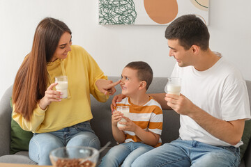 Sticker - Little boy with his parents drinking milk on sofa at home