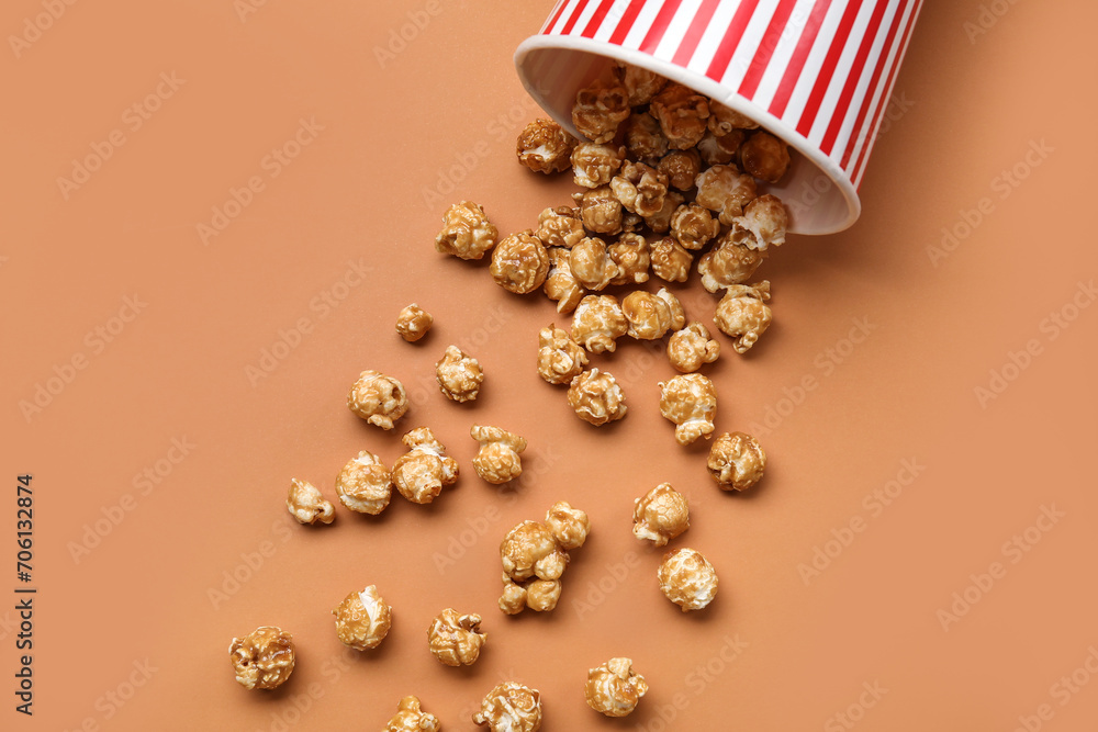 Bucket with tasty popcorn on brown background