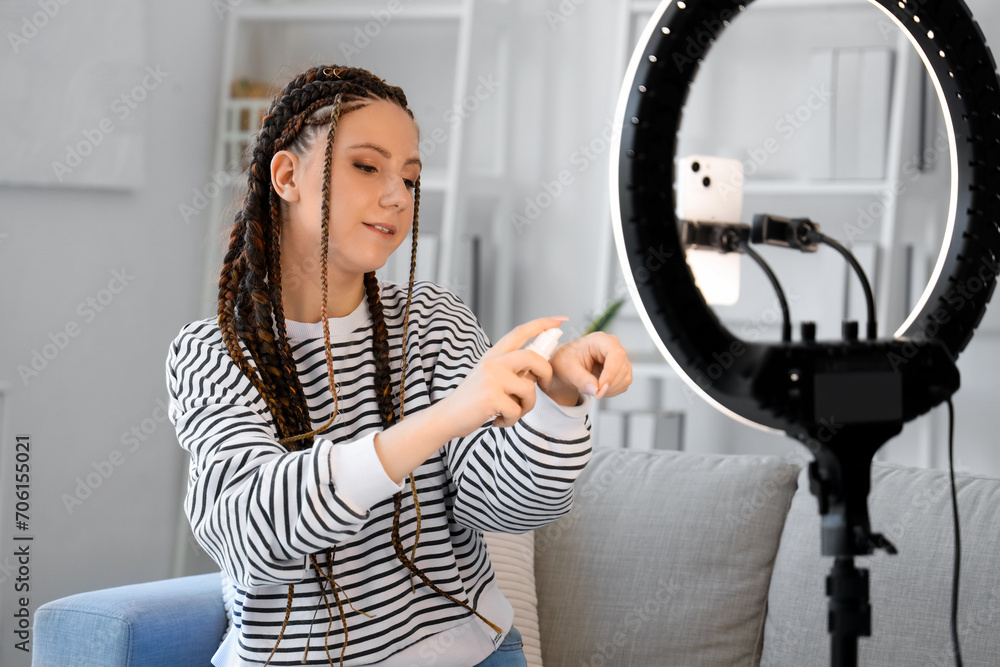 Beauty blogger with makeup foundation recording video at home