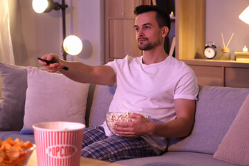 Poster - Young man with popcorn watching TV at home in evening