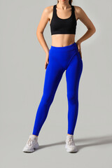 Wall Mural - Sporty young woman in blue leggings on light background