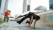 Panorama shot of break dancer perform b-boy performance and energetic footstep at city view. Break dancer moving to funky music and cheering young male hipster. Outdoor sport 2024. Sprightly.