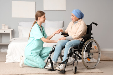 Poster - Mature woman after chemotherapy in wheelchair with nurse holding hands at home. Stomach cancer concept