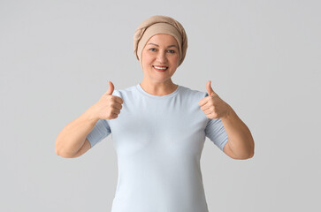 Sticker - Mature woman after chemotherapy showing thumbs-up on light background. Stomach cancer concept