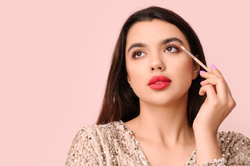 Poster - Beautiful young woman with brush applying eyeshadows on pink background