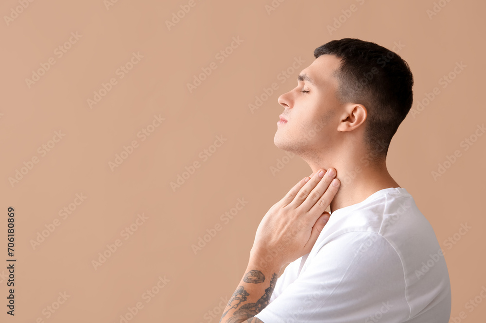 Young man with thyroid gland problem on beige background