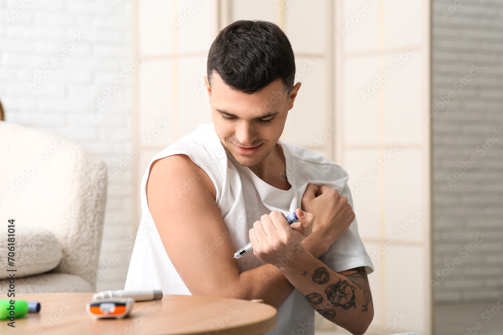 Diabetic young man using lancet pen at home